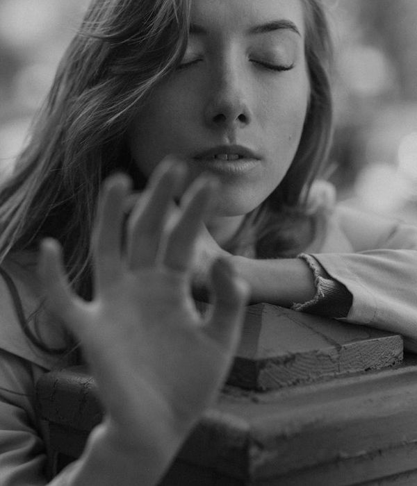 Woman in a calm yoga pose in a dark room with teal light.